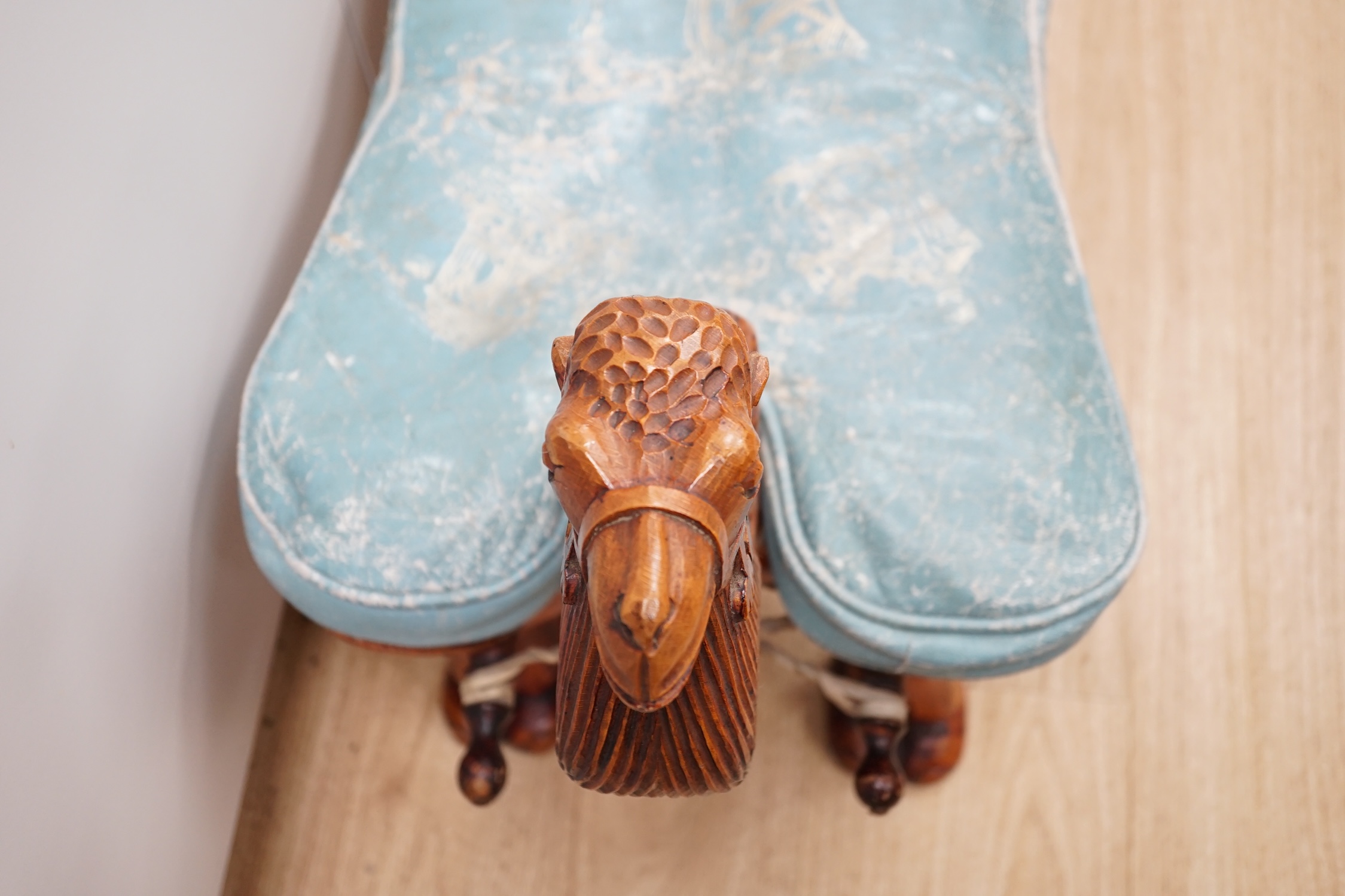 A carved wood foot stool in the form of a camel, blue stamped patterned leather cushion, 56cm high, 71cm wide. Condition - frame good, leather cushion worn